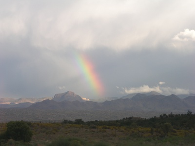 [Another rainbow coming down from the clouds into the hills arcing from upper left to lower right.]