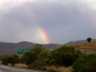 [Another rainbow a bit longer than the others. This one also arcs from upper left to lower right. Silver Springs road sign seen in foreground.]