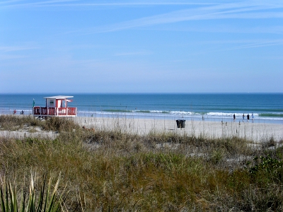 [In foreground are grassy dunes. Beyond it is the sand and then the Atlantic Ocean. Lifeguard shack with 360 degree red-painted railing.]