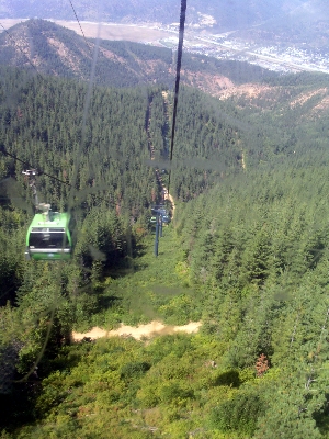 [View of other gondolas on side of the mountain as seen from inside of a gondola.]