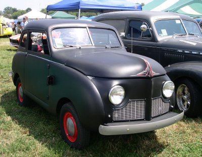 [Quite small and narrow black car with red-rimmed wheels.]