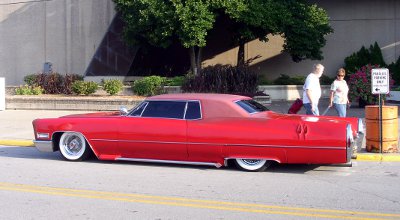 [Long red car with fender sides which are barely off the ground. Big white walls on the tires.]