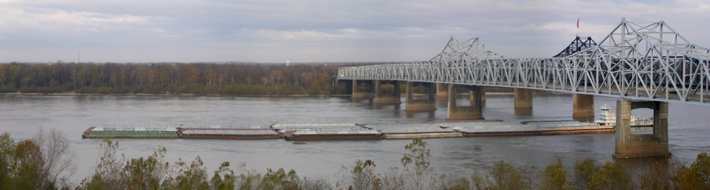 [Several photos were stitched together to create the entire scene. Tugboat under the bridge pushing 6 rows of barges.]