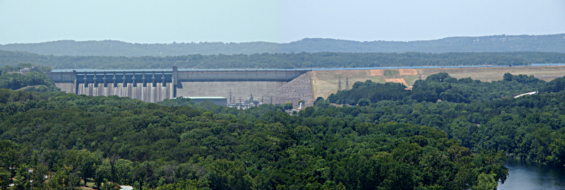 [Several photos stitched together showing the dame and the hillside to its right which holds the water in the lake. Lush greenery is both in front of and beyond the dam.]