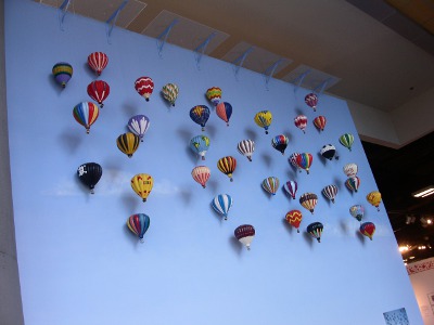 [40 small balloons models offset from a blue wall.]