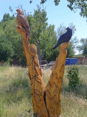 [Wooden carving of birds atop carved sunflower posts.]