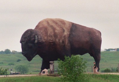 [Side view of sculpture as seen from a distance. Top of person's head almost makes it to the 