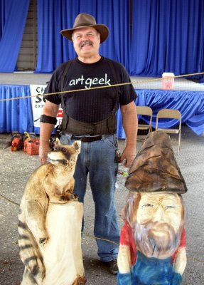 [Burt wearing art geek t-shirt standing behind two of his stump creations.]