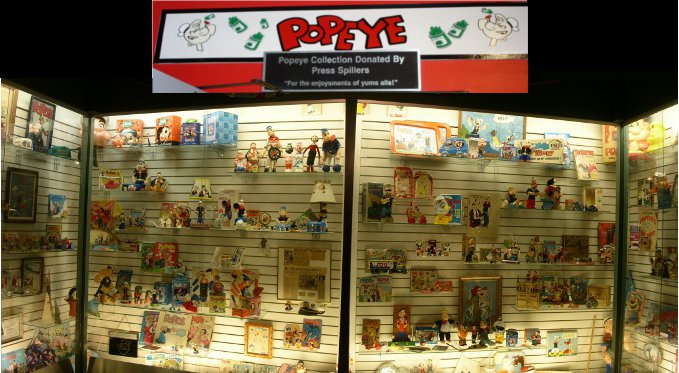 [Several photographs stitched together to show the showcases full of Popeye memorabilia.]