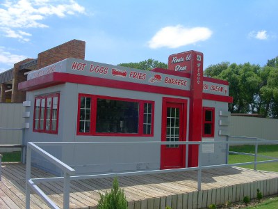 [Small red-trimmed grey portable building.]