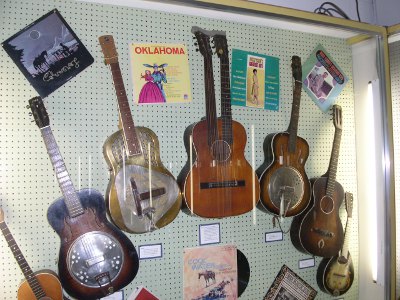 [Six guitars hung on a wall including a double-necked guitar.]