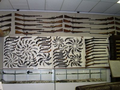 [Huge display of rifles and pistols artistically mounted on a wall.]