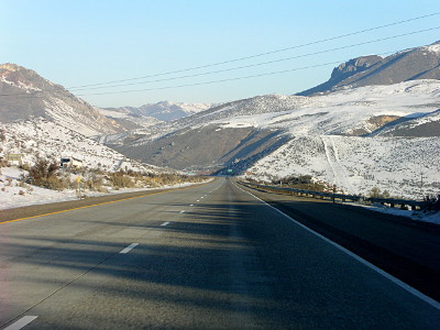 [Highway through mountains which have a dusting of snow on them.]