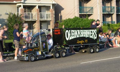 [Man driving a mini truck and trailer advertising this Shrine group.]