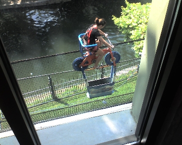 [Girl on a cycle on a rope with a counterweight under it.]