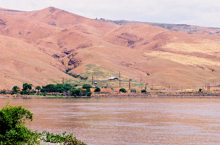 [River view in canyon with farm house on hillside.]