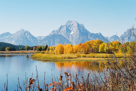 [Colorful trees reflected in lake with Tetons as a backdrop.]